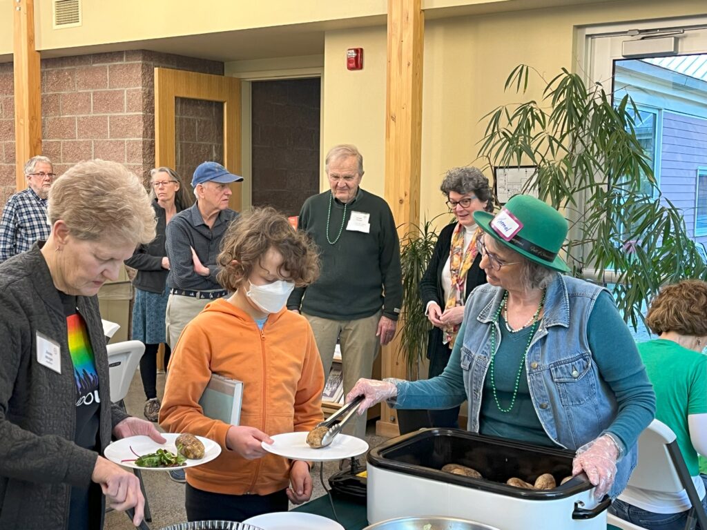 people serving themselves and each other at a Thursday community dinner